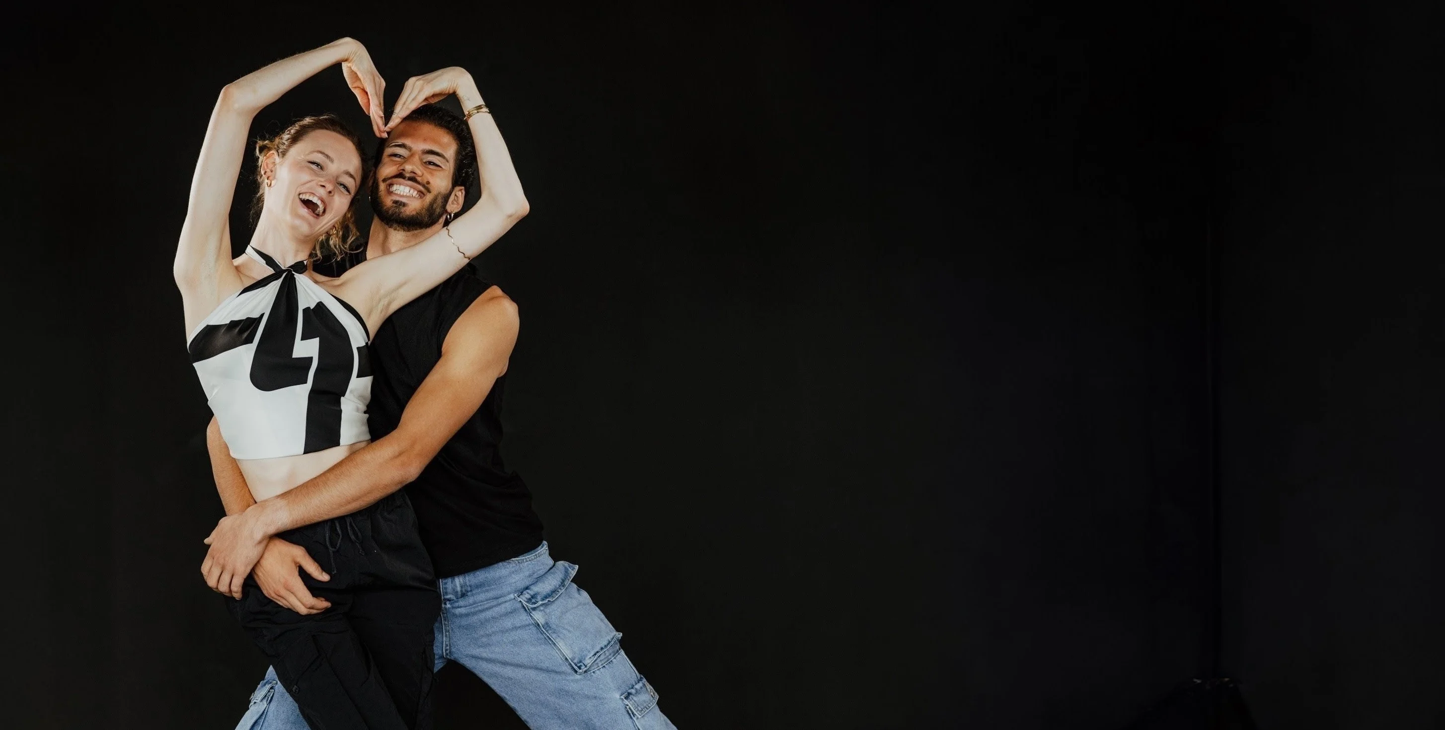 Ursula und Stamatis lachen und formen mit den Armen ein Herz